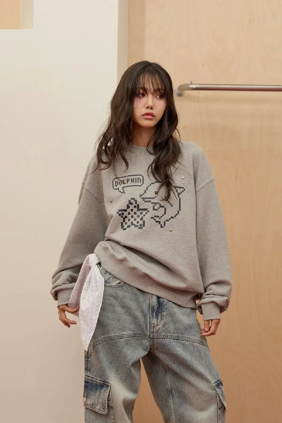 Model wearing grey Dolphin pixel art sweatshirt and loose denim cargo pants with white scarf