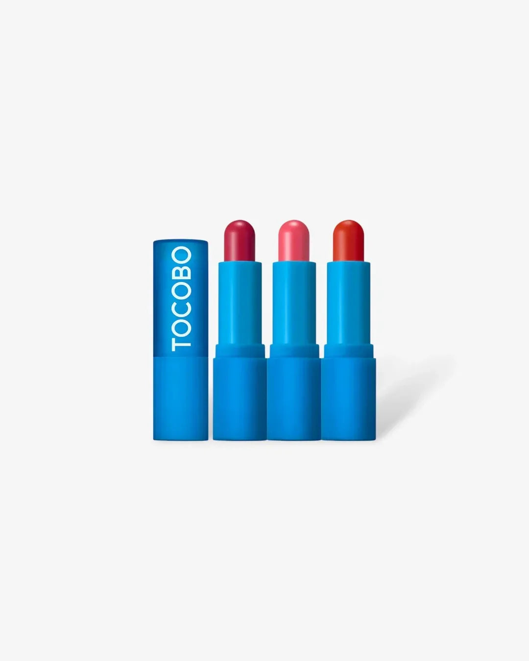 Three blue TOCOBO lip balms in red, pink, and coral shades with one blue cap on white background