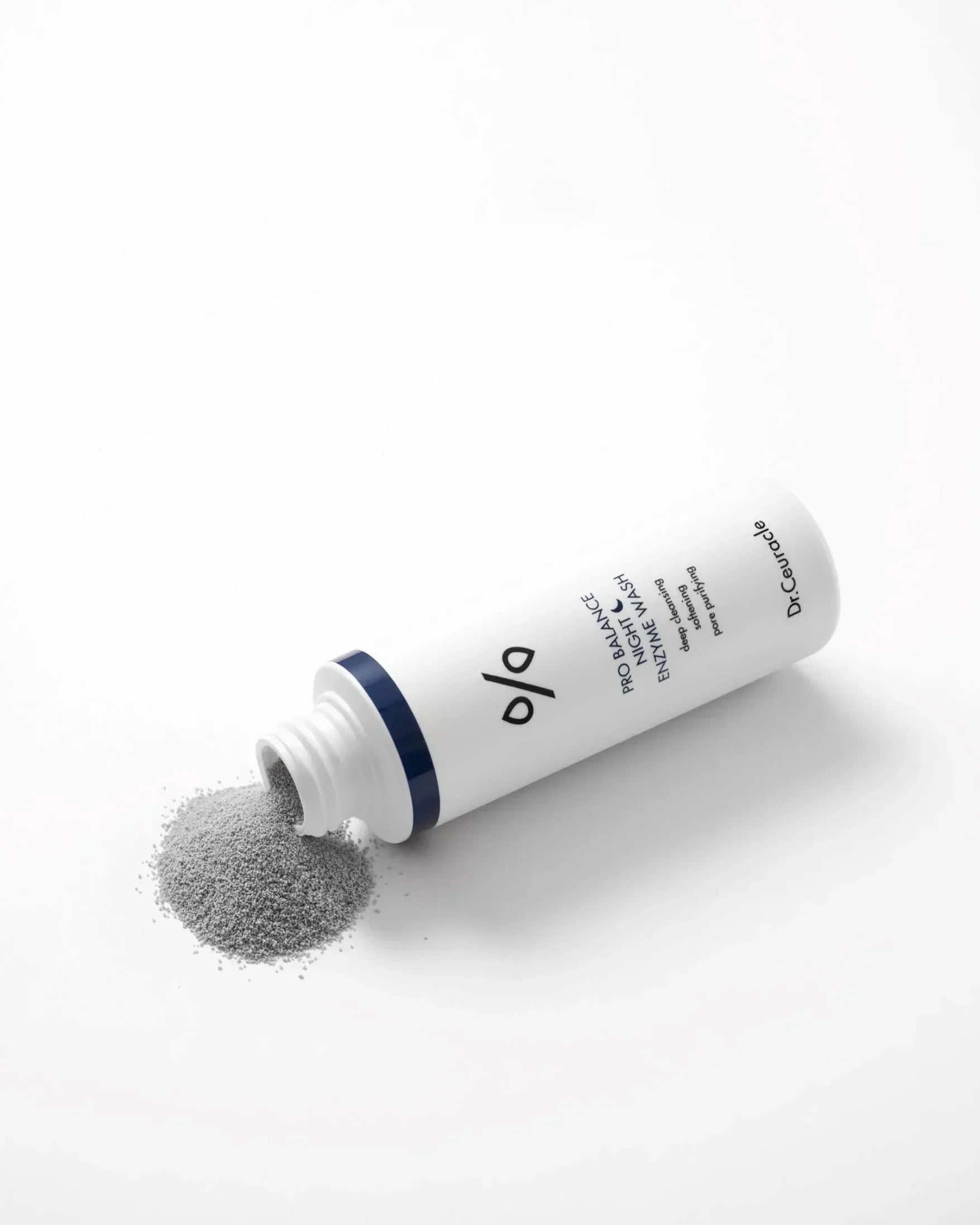 White tube of Pro Balance Night Enzyme Wash by Dr. Ceuracle with spilled gray powder on white background