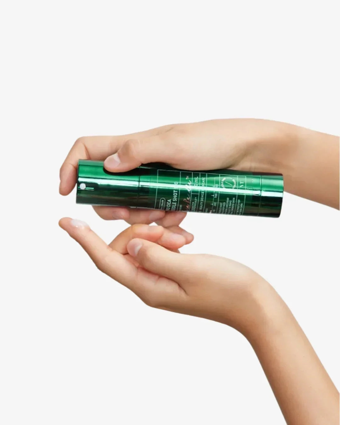 Close-up of hands dispensing white cream from green Pro Cica Reedle Shot skincare bottle