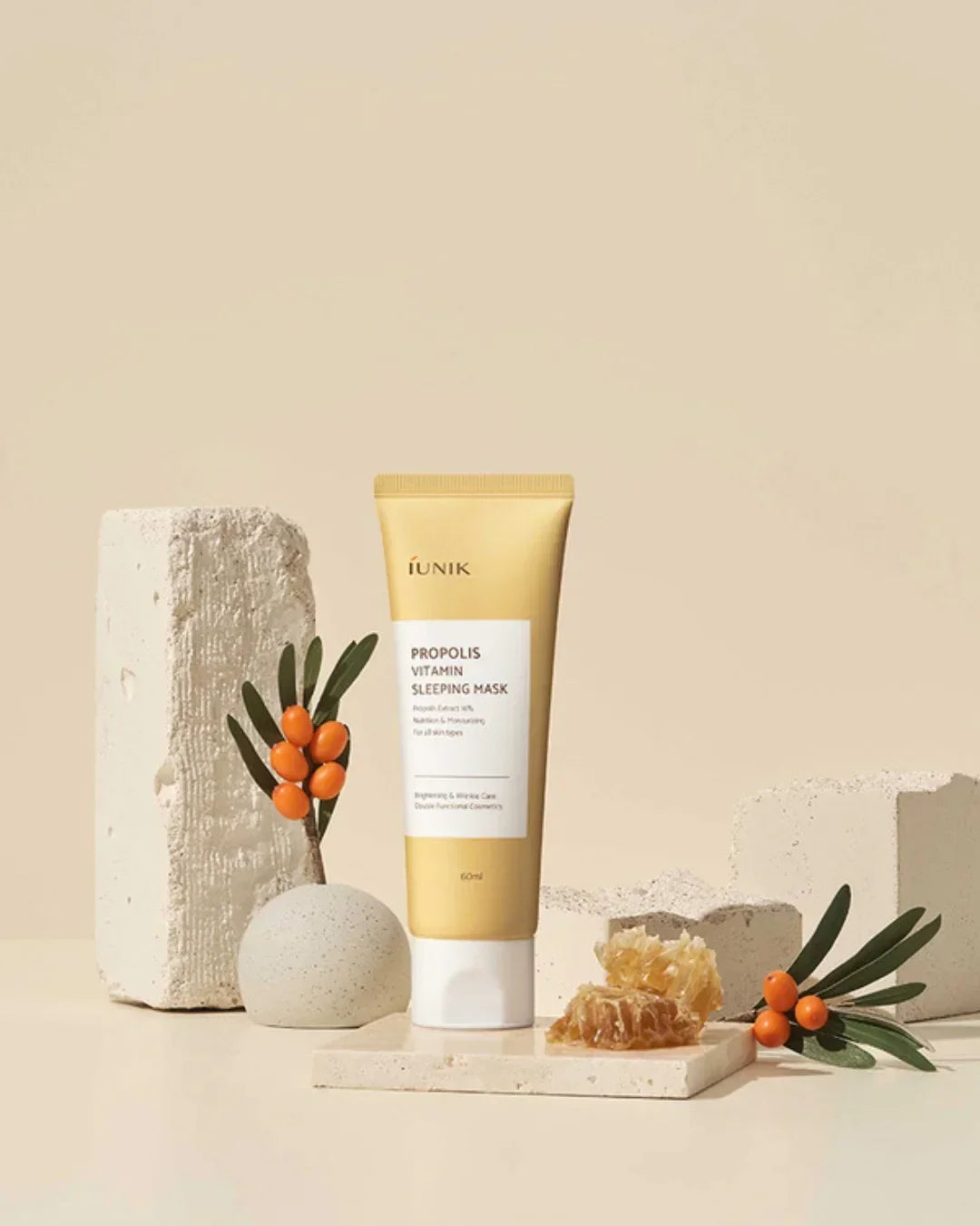 iUNIK Propolis Vitamin Sleeping Mask tube surrounded by honeycomb and orange berries on neutral stone blocks