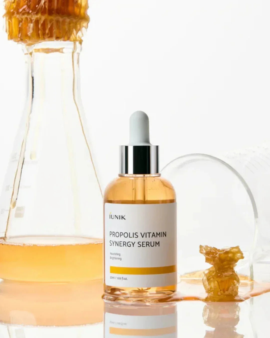 iUNIK Propolis Vitamin Synergy Serum bottle with dropper, honeycomb piece and glassware with golden liquid