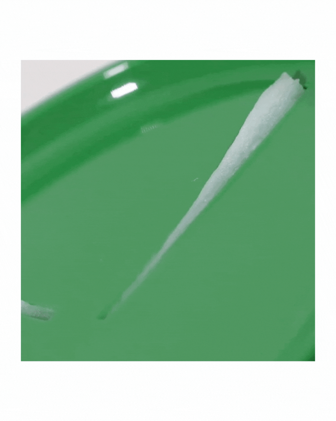 Pure Grinding Cleansing Balm texture spread in a smooth, creamy white strip on green surface