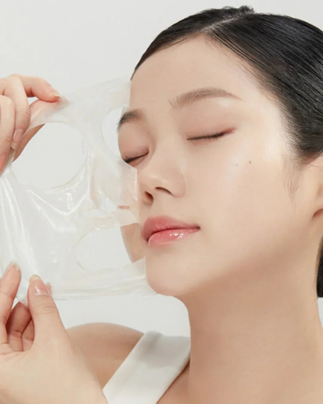 Close-up of woman gently peeling off a transparent facial mask for skincare