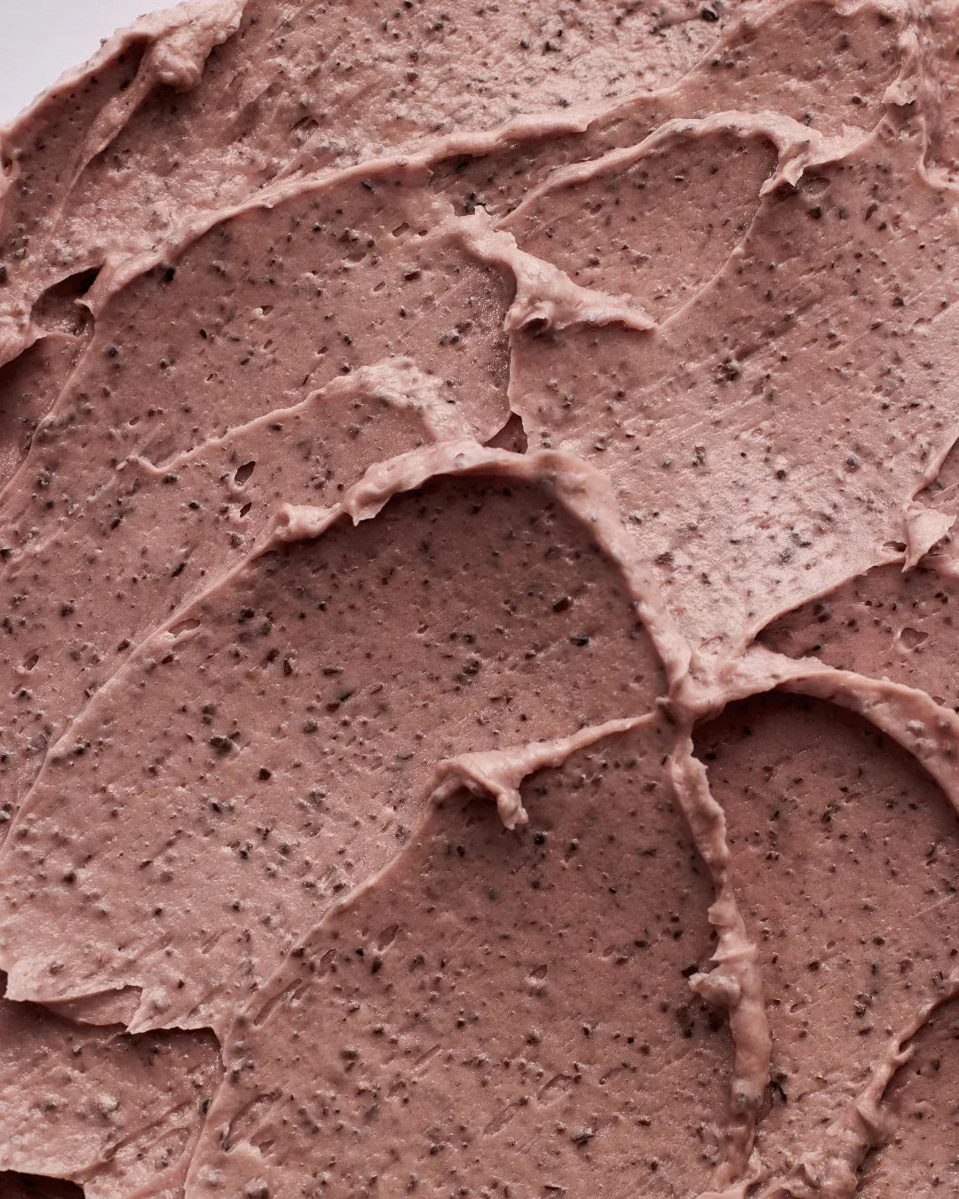 Close-up of textured red bean pore mask spread showing creamy skincare product with dark exfoliating particles