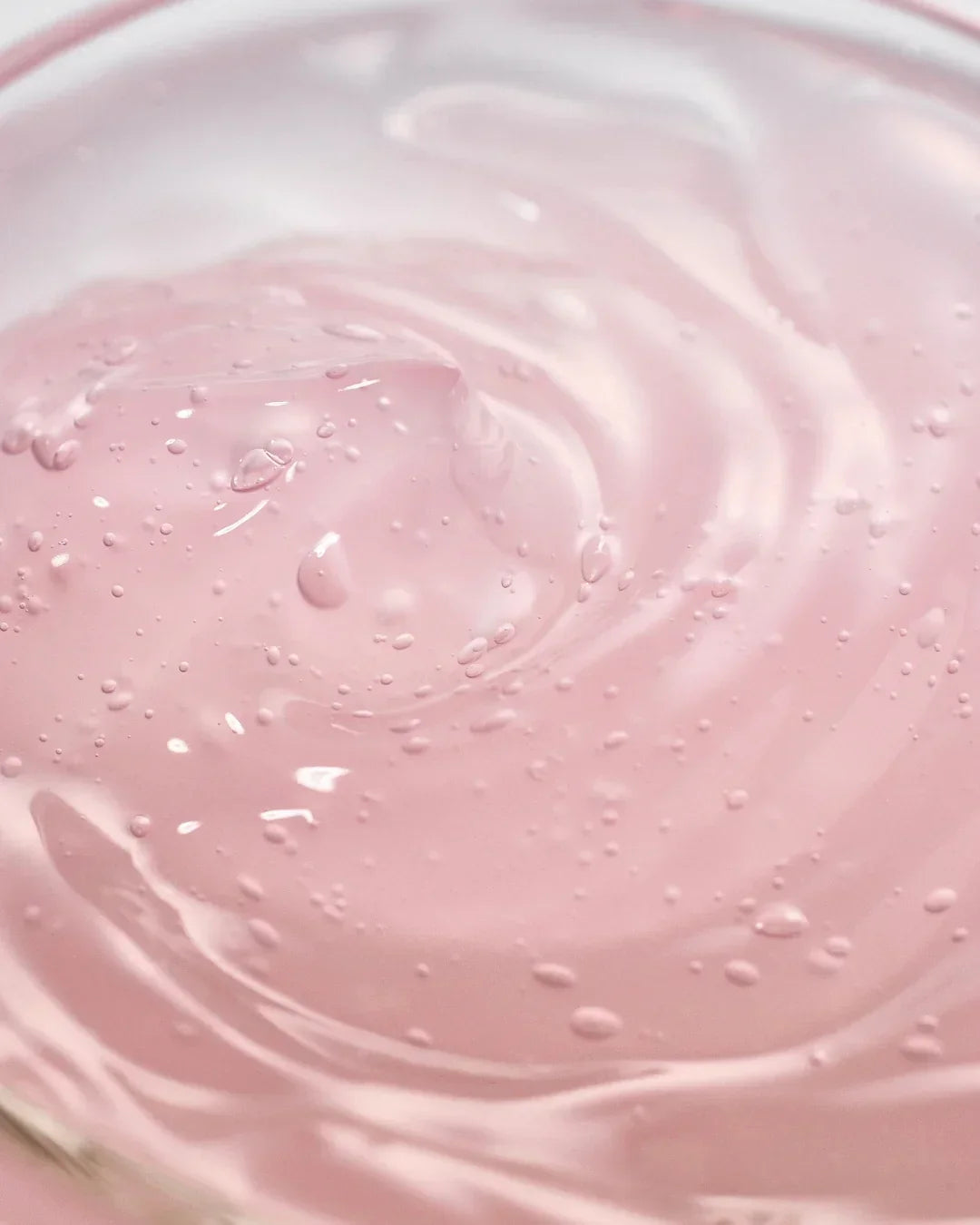 Close-up of smooth pink gel texture with small bubbles, skincare or beauty product