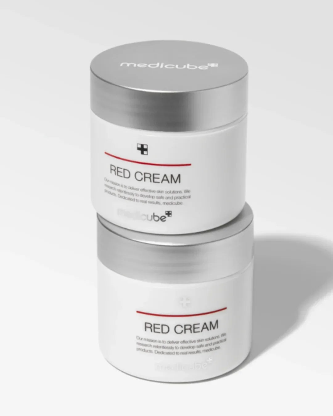Two white Medicube Red Cream skincare jars with silver lids on a light background