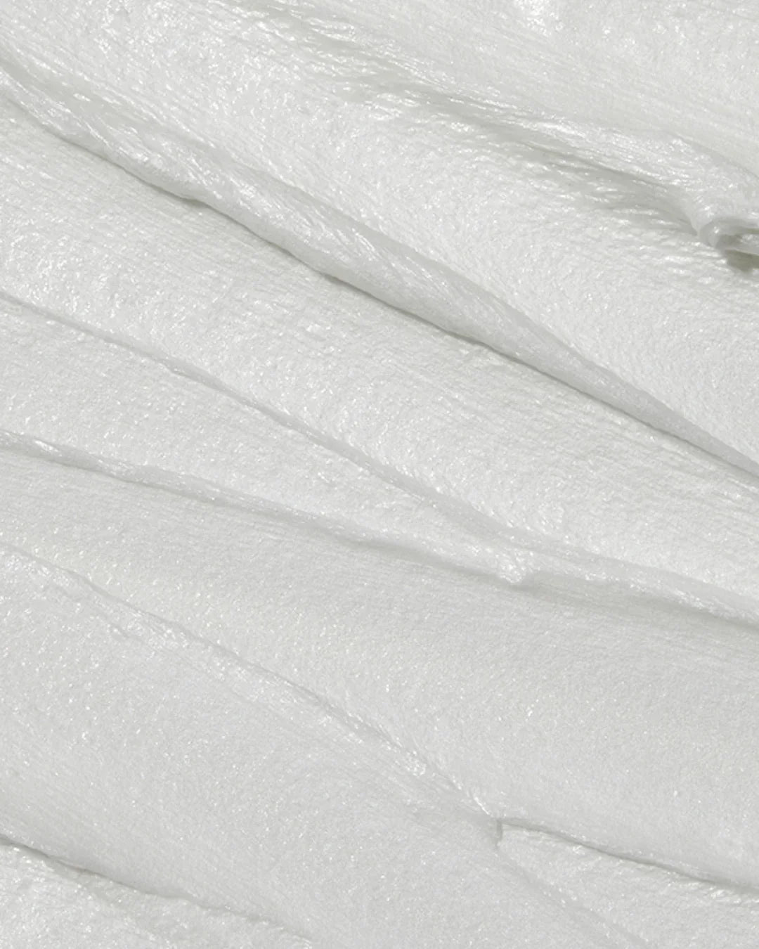 Close-up texture of smooth white foam cleanser spread in layers