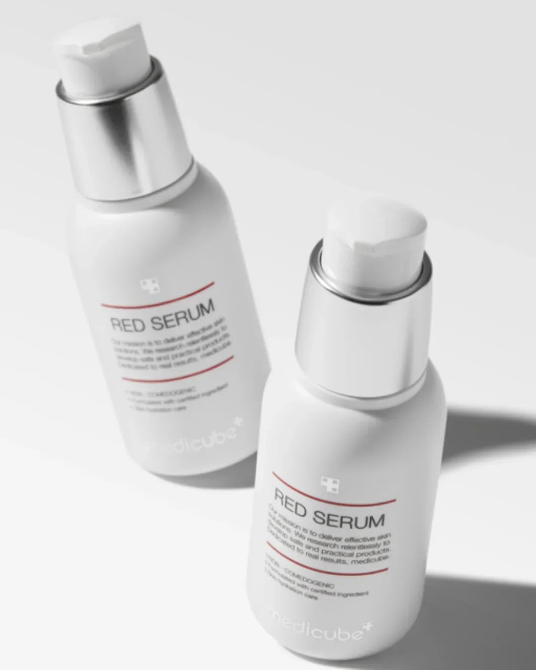 Two white Medicube Red Serum bottles with silver pump caps on a white background