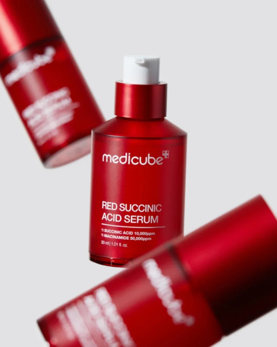 Medicube Red Succinic Acid Serum 30ml in red bottle with pump on gray background