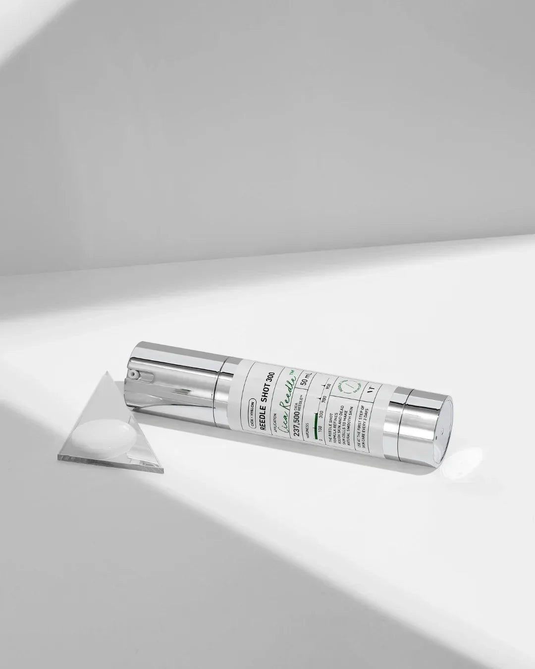 Reedle Shot 300 moisturizing skin care cream bottle on white surface with clear acrylic triangle