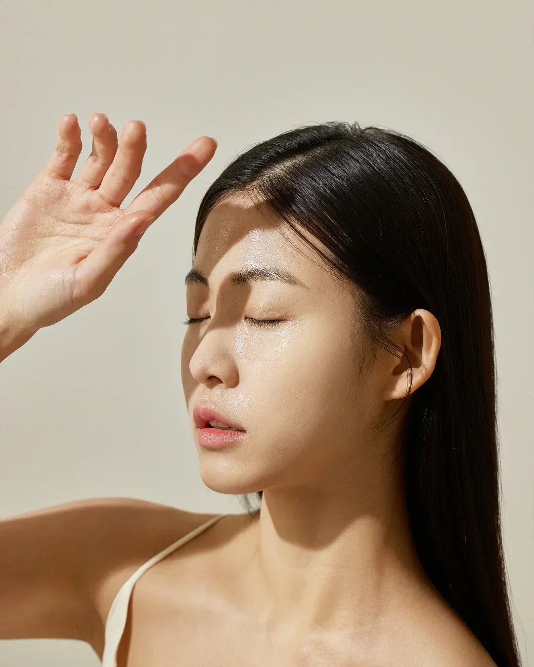 Close-up of a woman with clear skin shielding her face from sunlight, showcasing natural beauty