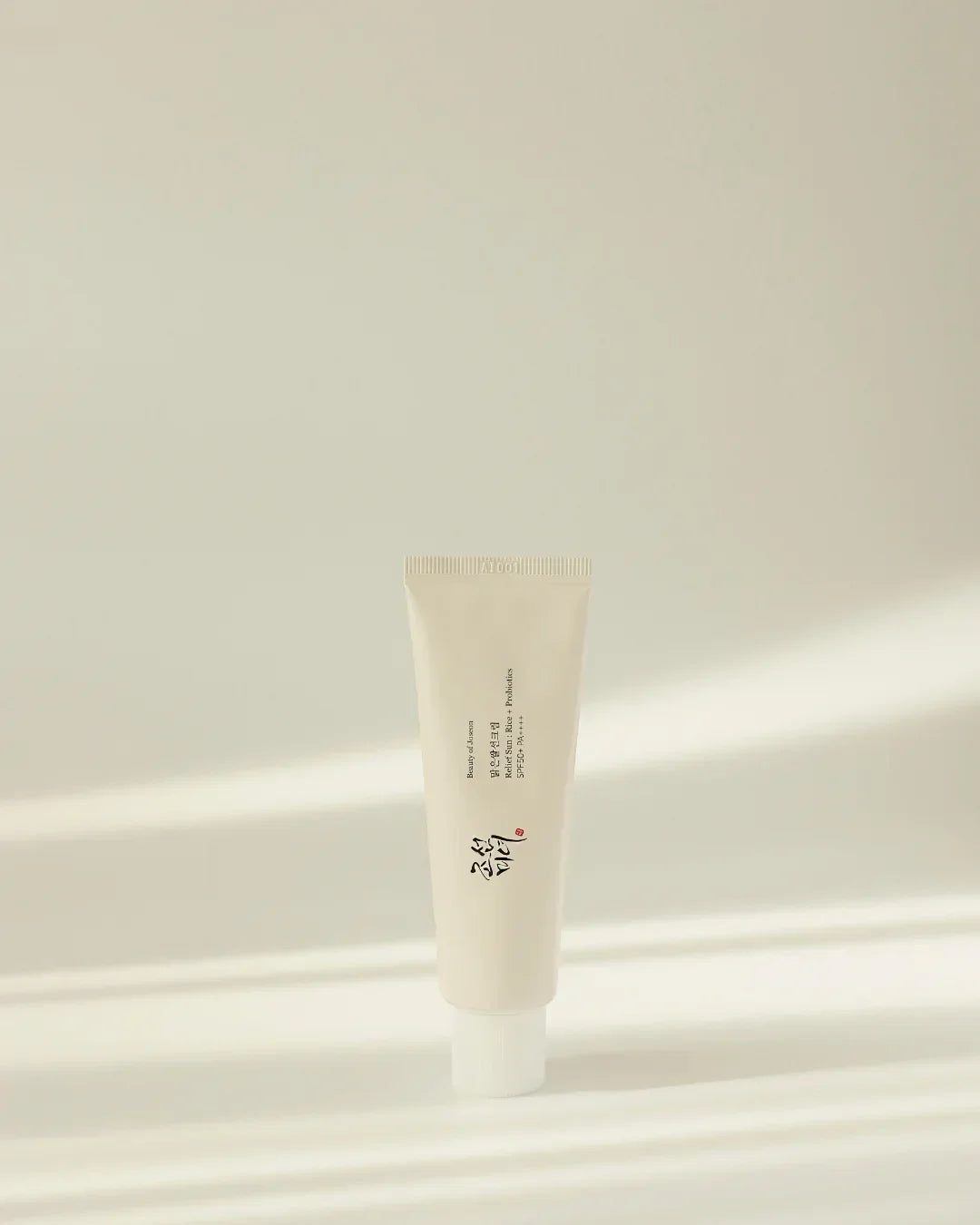 Minimalist tube of Relief Sun Rice Probiotics SPF50+ PA+++ sunscreen on beige background