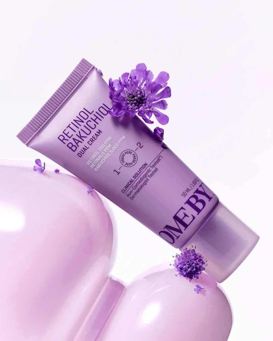 Retinol Bakuchiol Dual Cream tube with purple flowers on glossy pink balloons
