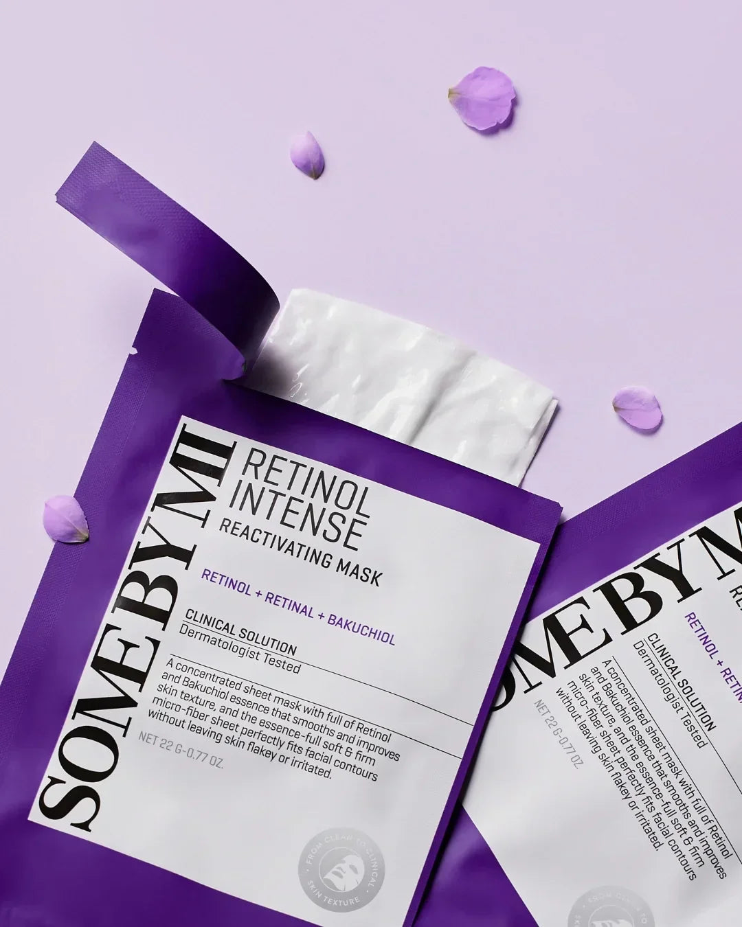 Purple packaging of SOME BY MI Retinol Intense Reactivating Mask with white sheet mask and purple flower petals