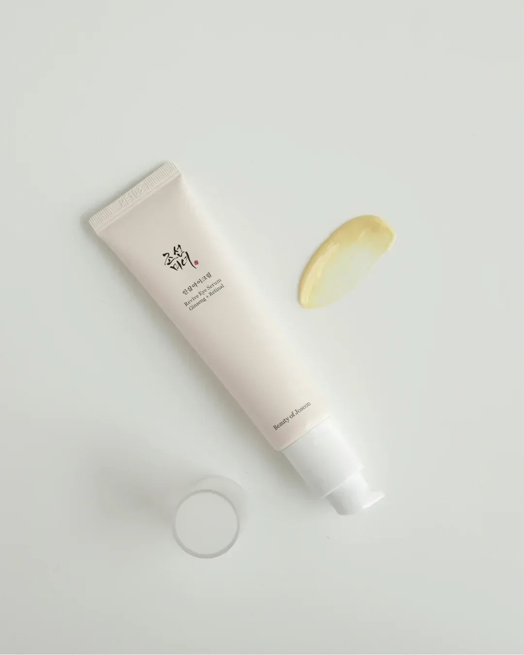 Tube of Beauty of Joseon Revive Eye Serum with ginseng and retinal, cream swatch on white surface