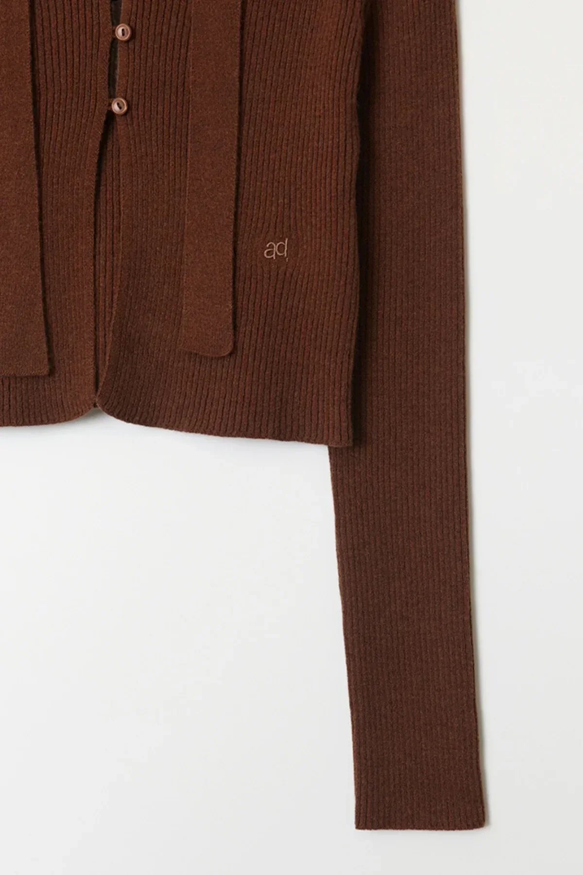 Close-up of brown ribbed knit V-neck cardigan sleeve and front with buttons on white background