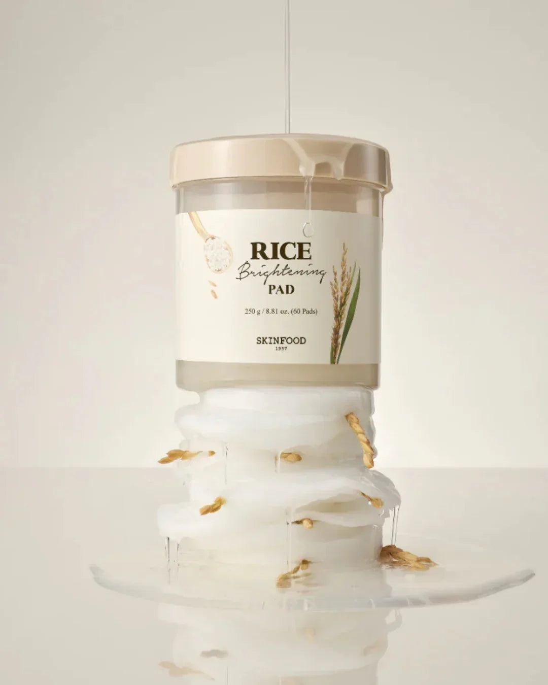 Skinfood Rice Brightening Pad container with cotton pads and rice grains on a reflective surface