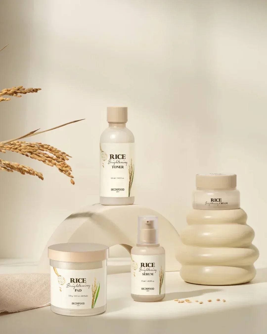 Skinfood Rice Brightening skincare set with toner, serum, cream, and pads on beige background