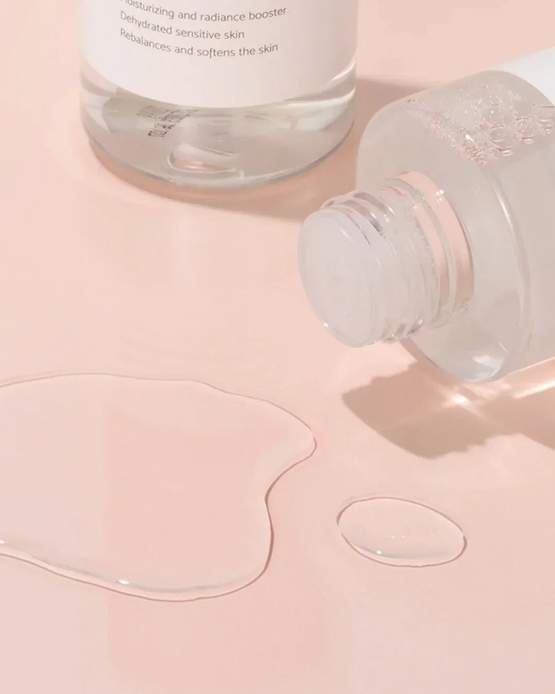 Rose Galactomyces Essential Toner 200ml clear liquid spilled on pink surface with open bottle