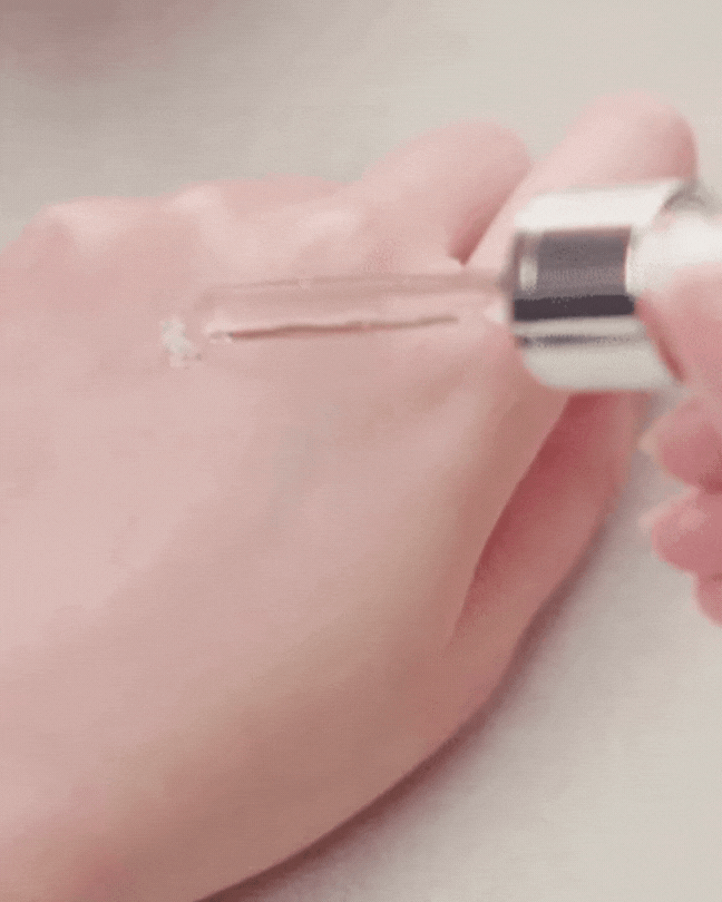 Applying clear Rose Galactomyces Synergy Serum with dropper on hand skin showing smooth texture