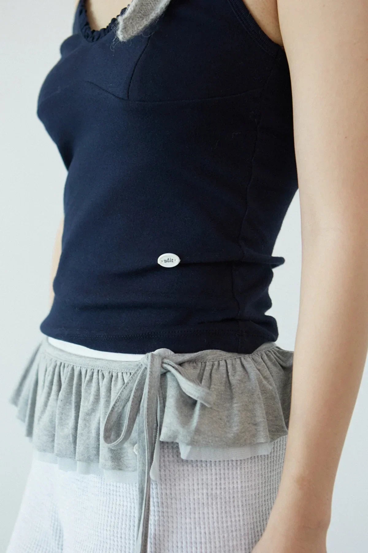 Close-up of navy ruffle bra top with grey ruffled trim and tie detail on model