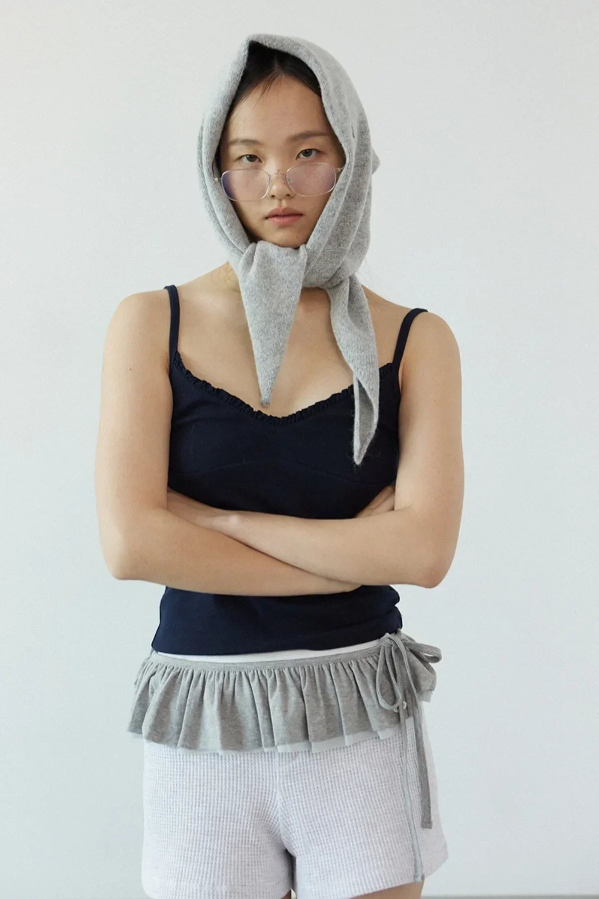 Model wearing navy ruffle bra top with gray ruffle waist detail, gray knit shorts, and gray headscarf in studio