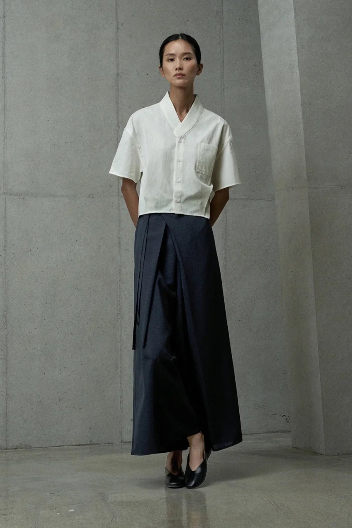 Model wearing navy blue wide-leg wrap salangsalang pants and white short-sleeve button-up top in studio