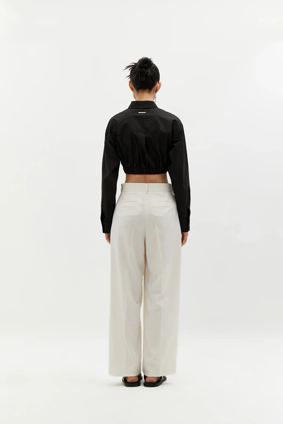 Model wearing black cropped banding cotton shirt and white wide-leg pants, back view on white background