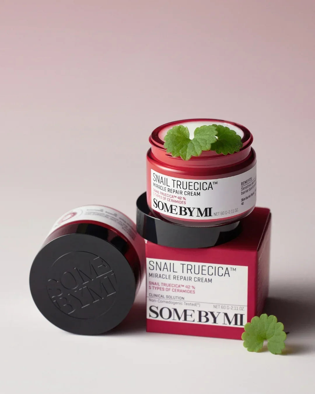 SOME BY MI Snail Truecica Miracle Repair Cream jar and packaging with green leaves on a pink background