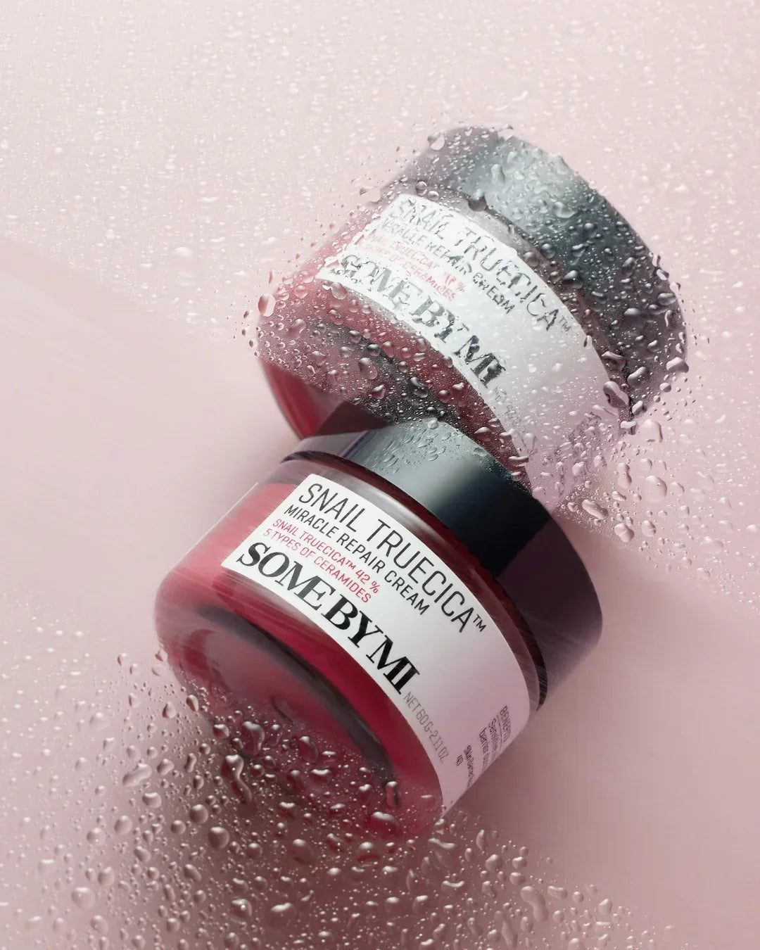 SOME BY MI Snail Truecica Miracle Repair Cream jar with water droplets on pink surface
