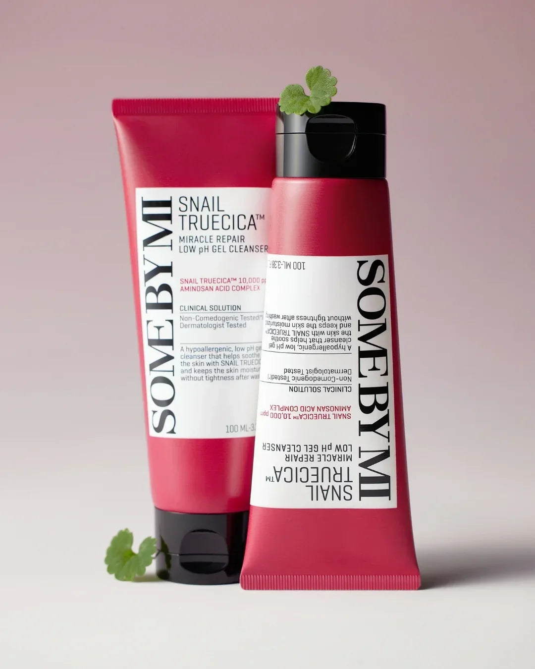 SOME BY MI Snail Truecica Miracle Repair Low pH Gel Cleanser tubes with green leaves on pink background