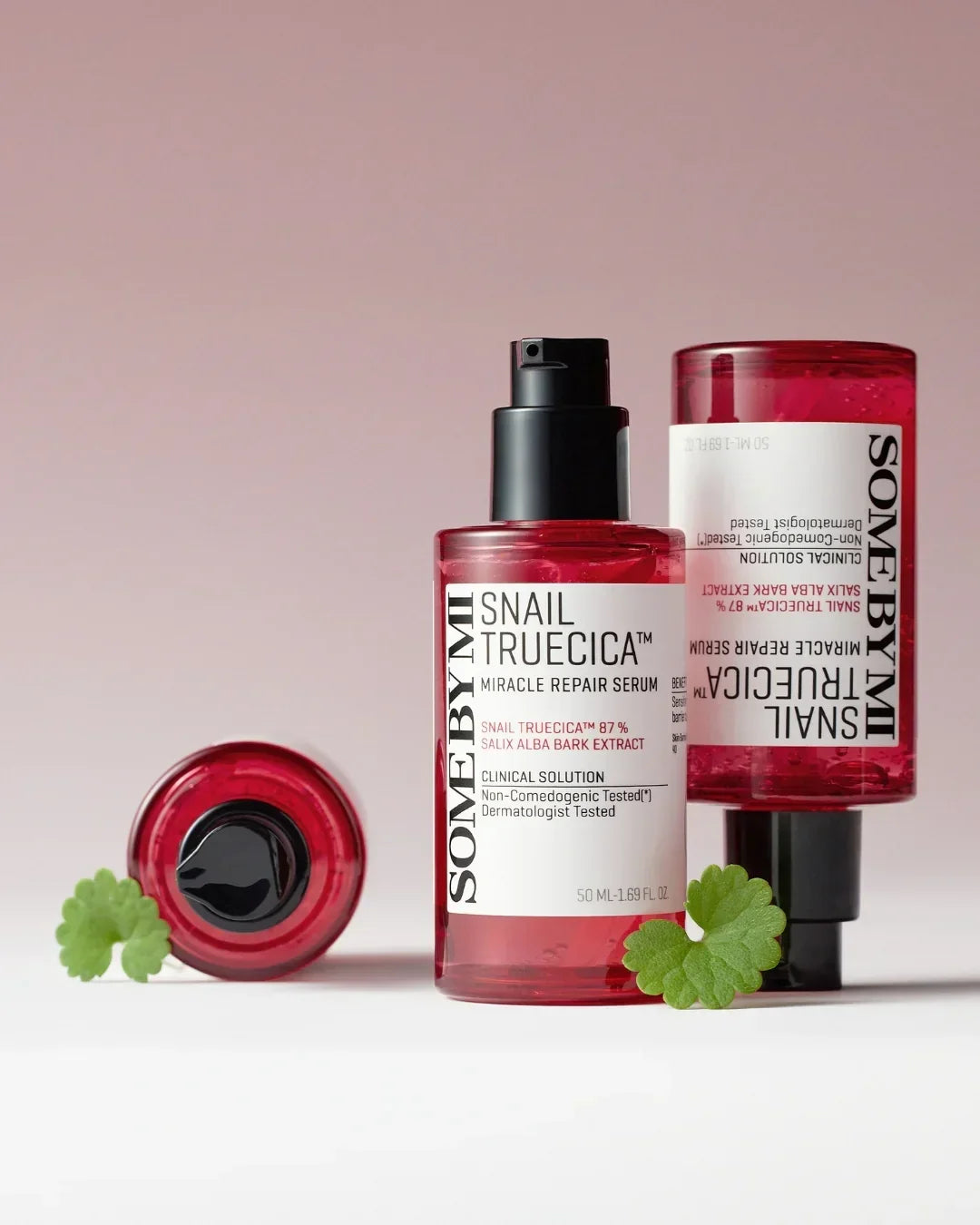 Some By Mi Snail Truecica Miracle Repair Serum 50ml bottles with green leaves on a pink background