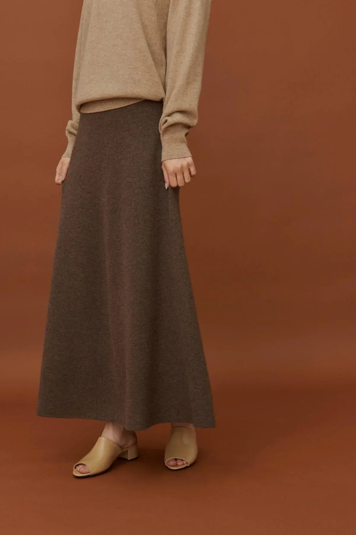 Woman wearing soft brown A-line knit skirt with beige sweater and beige open-toe mule heels