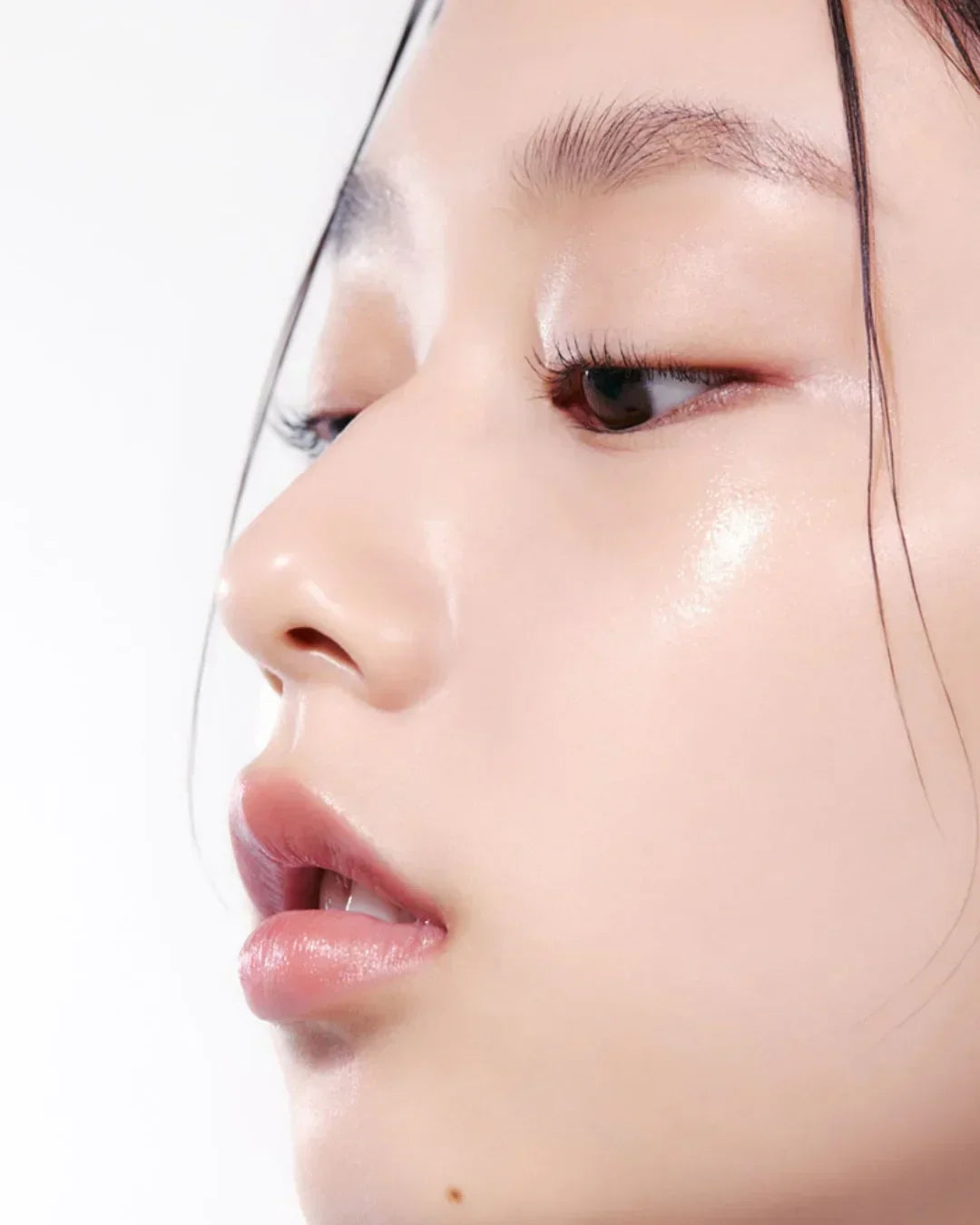 Close-up of a woman's glowing smooth skin with natural makeup against white background