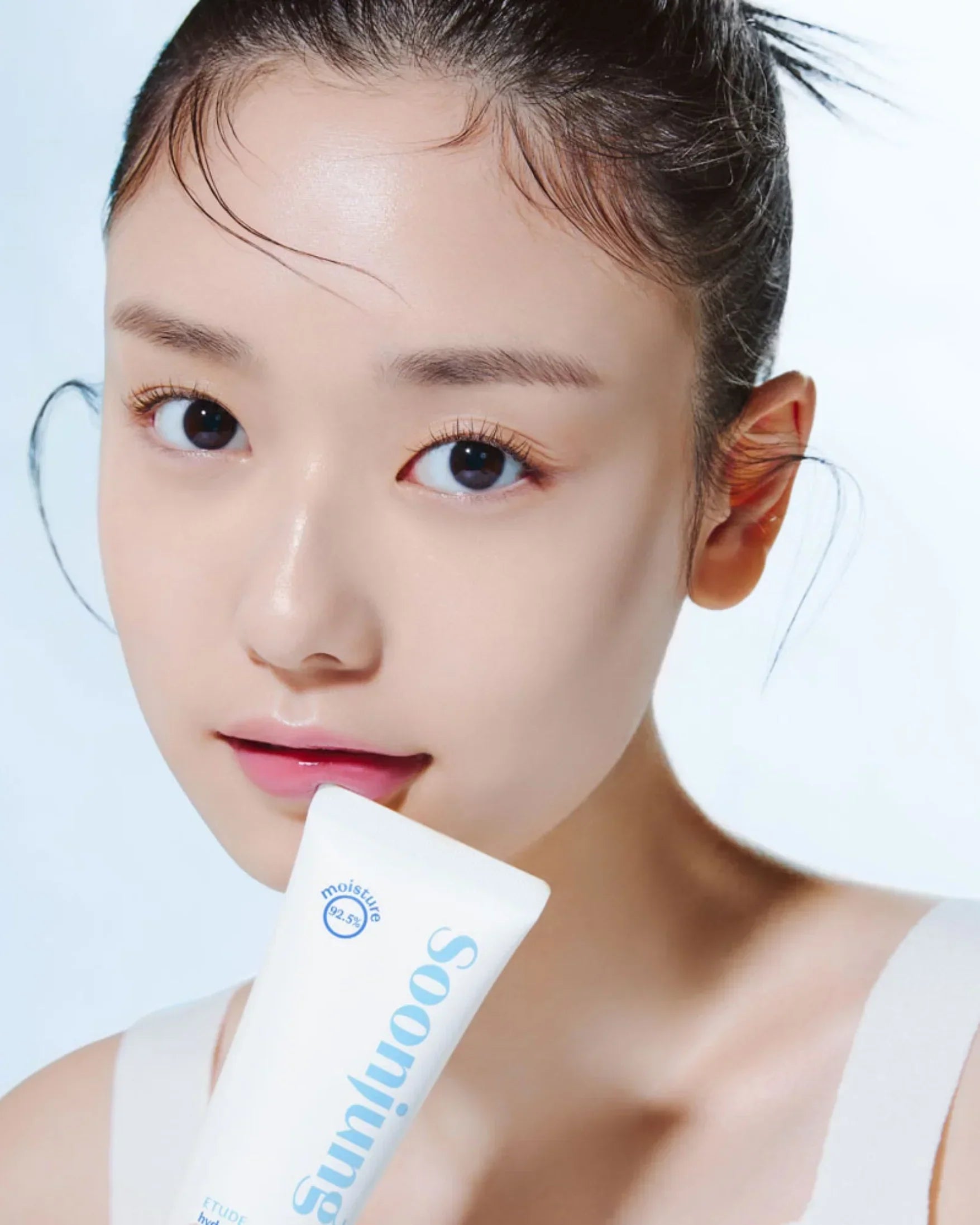 Close-up of young woman with clear skin holding Soonjung moisturizing cream tube