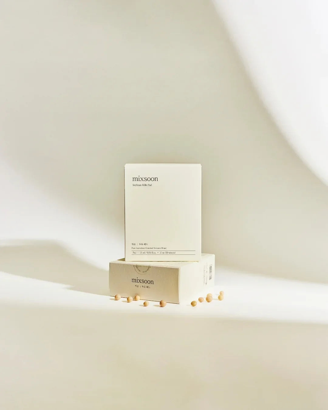 Mixsoon Soybean Milk Pad skincare product boxes with scattered soybeans on white background