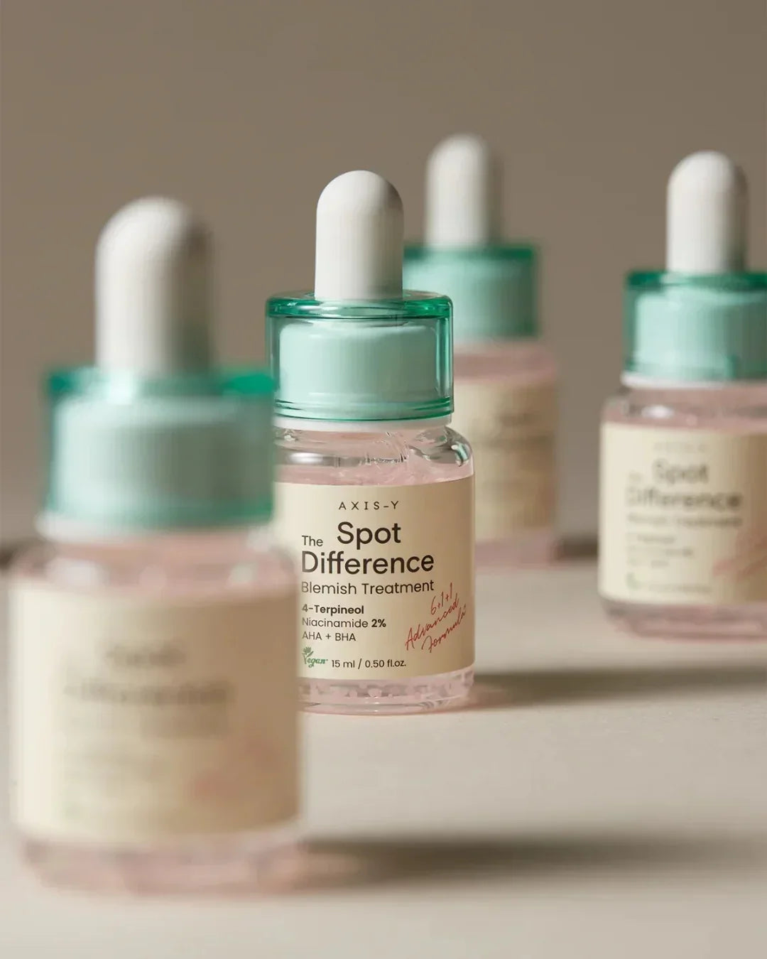 Axis-Y Spot Difference blemish treatment serum bottles with mint green droppers on beige surface