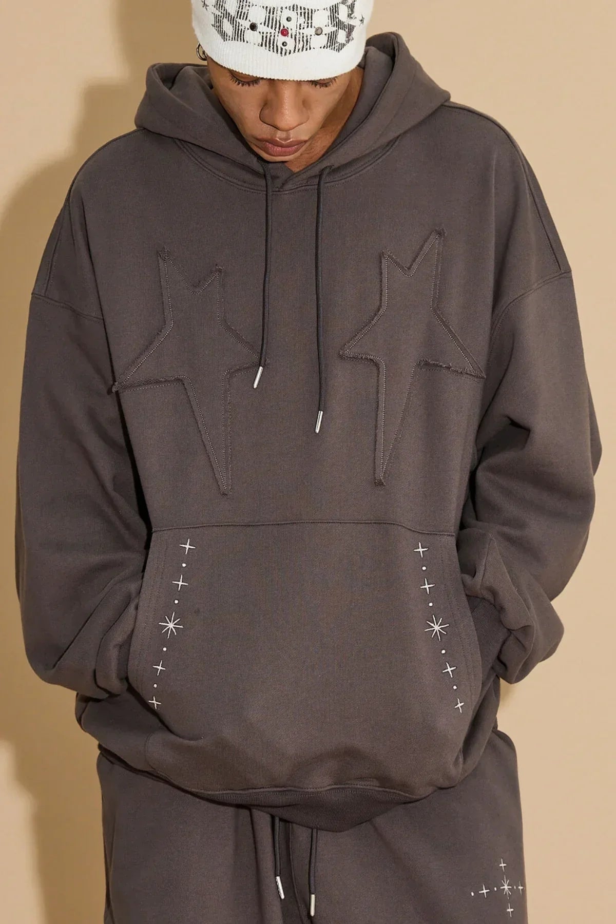 Charcoal hoodie with raised star appliques and white star embroidery on front pocket, worn with matching pants