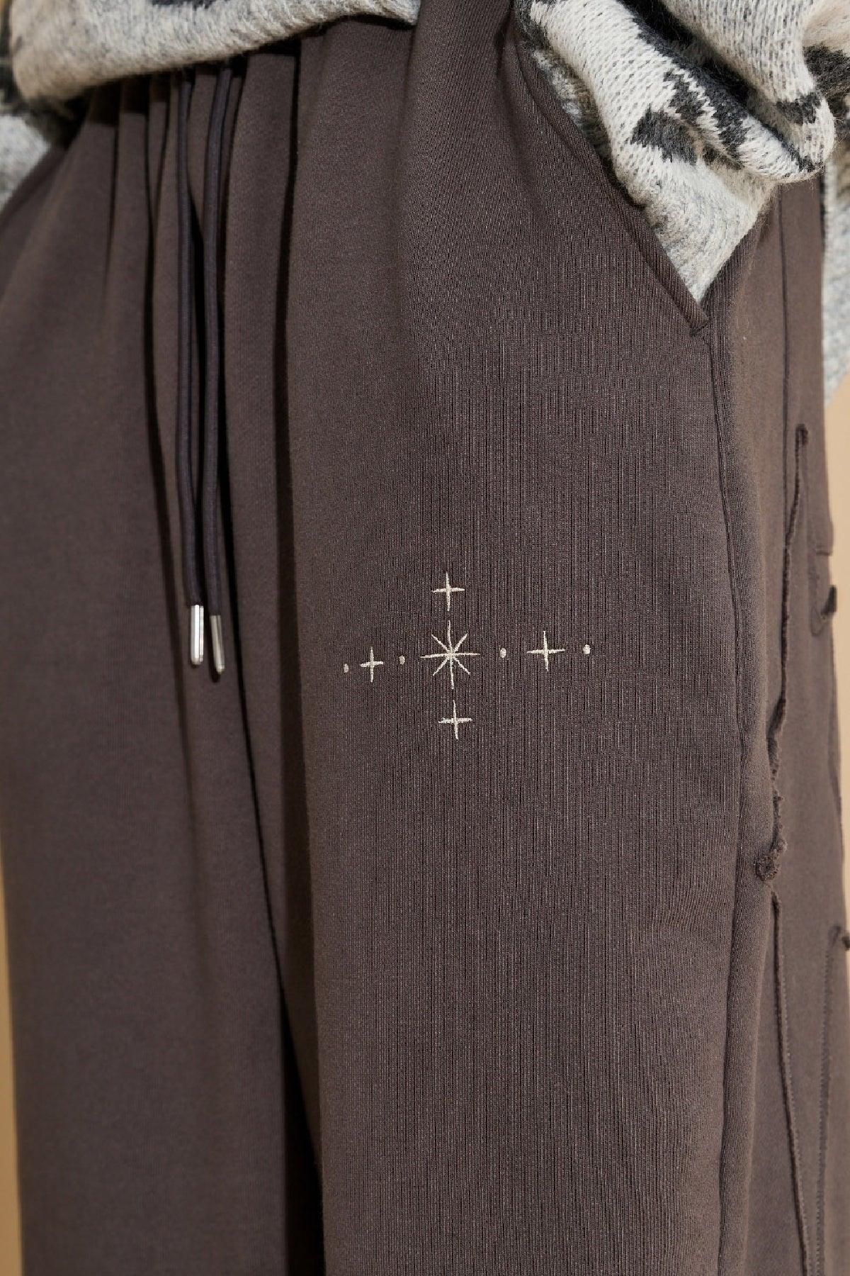 Close-up of charcoal sweatpants with star appliqué embroidery detail and drawstring waist