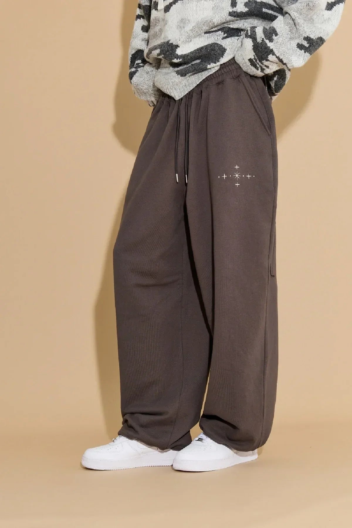 Model wearing charcoal star applique embroidery sweatpants with drawstring and white sneakers