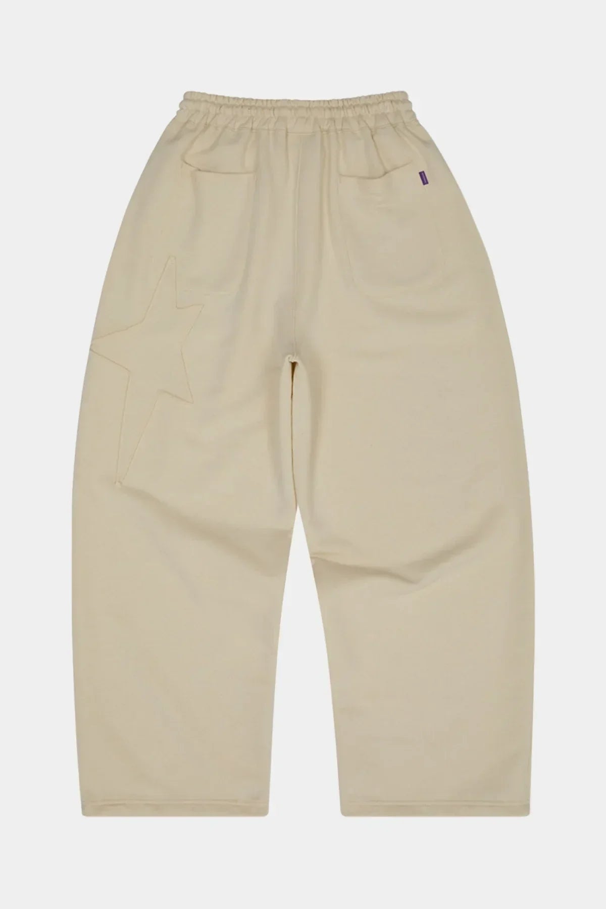 Ivory sweatpants with elastic waistband, back pockets, and star appliqué embroidery on left leg
