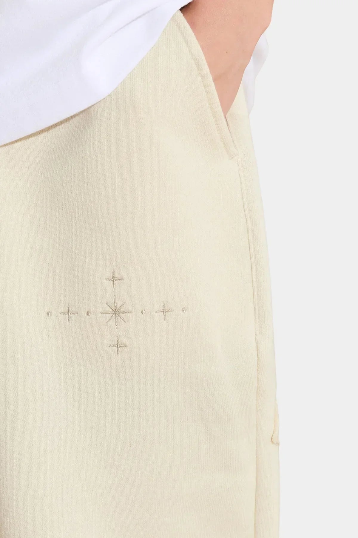Close-up of ivory sweatpants with star applique embroidery detail and side pocket