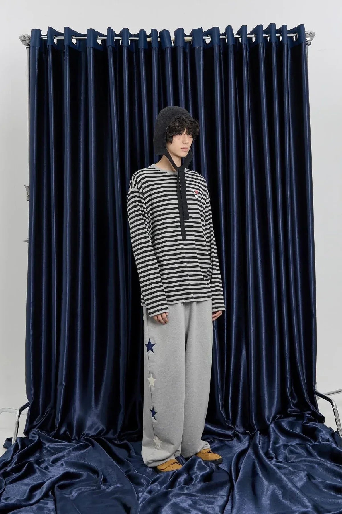 Model in grey star sweatpants and striped top on navy velvet backdrop, Korean fashion at Malkn