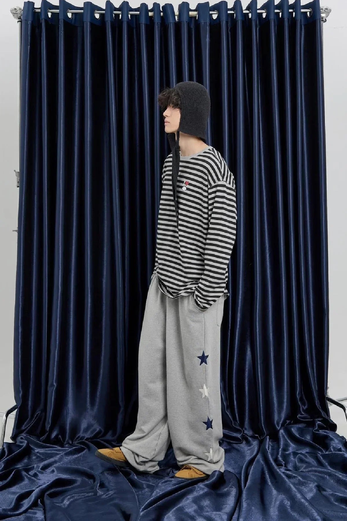 Model in grey star sweatpants and striped top, standing by navy velvet curtains, Malkn Korean fashion