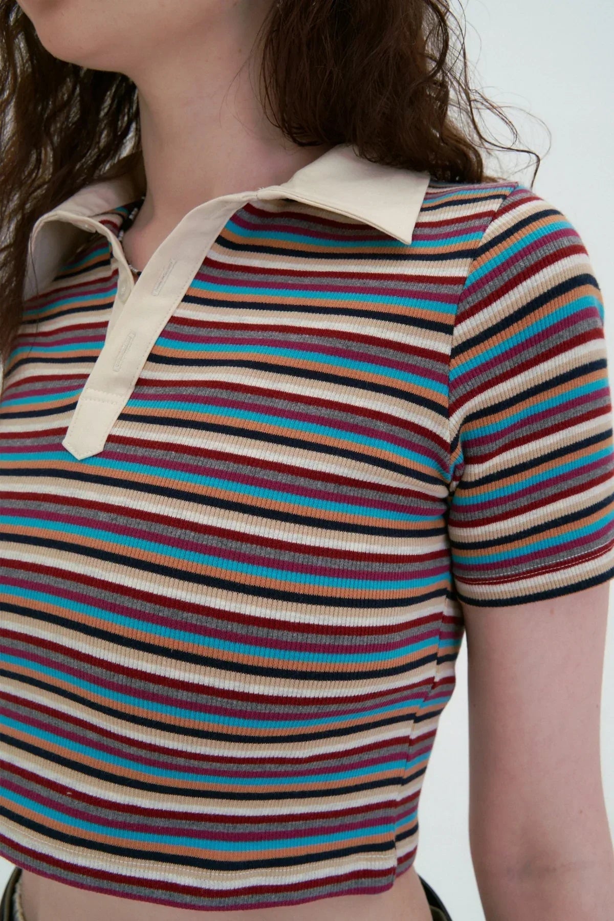 Close-up of woman wearing cropped striped polo t-shirt with beige collar and multicolor horizontal stripes