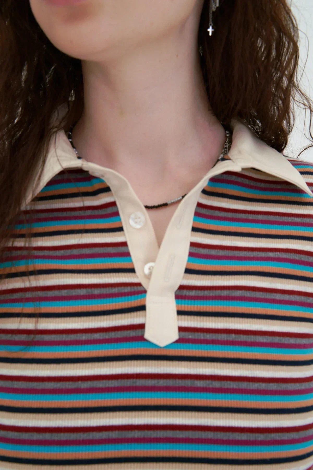 Close-up of a person wearing a striped ribbed polo shirt with beige collar and button placket