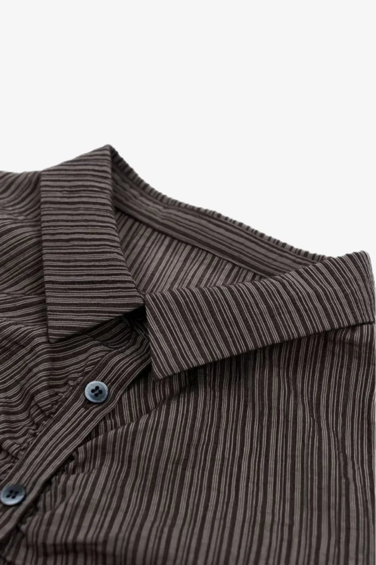 Close-up of brown striped shirt collar with blue buttons on white background