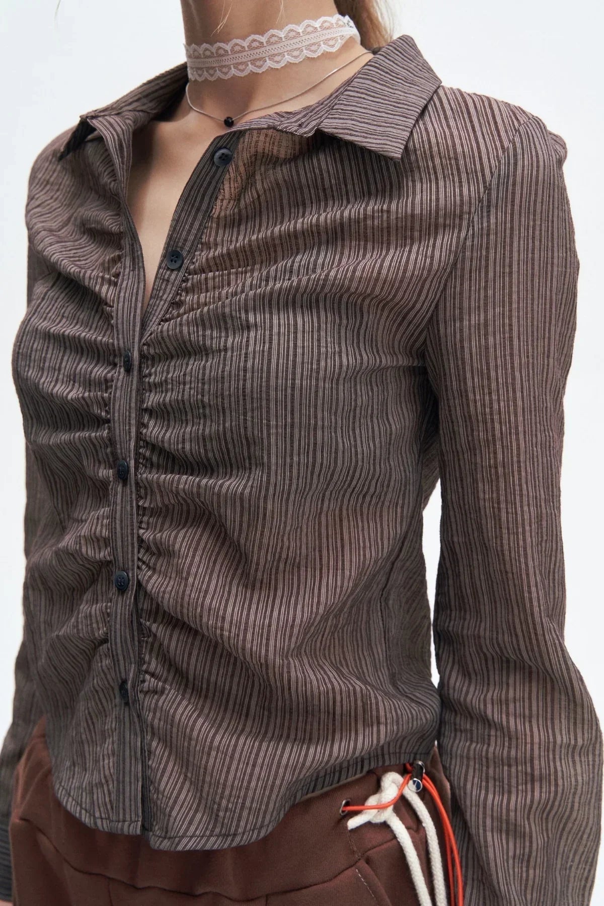 close-up of woman wearing brown striped ruched button-up shirt and brown pants with white drawstring