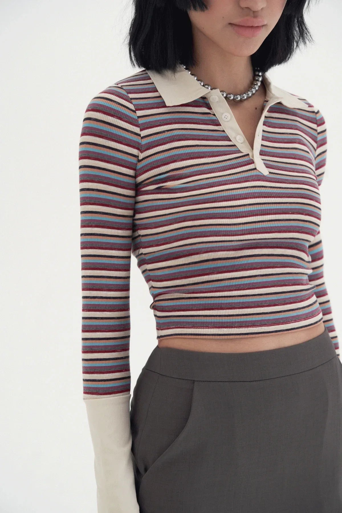 Close-up of woman wearing a striped long-sleeve cropped polo shirt with beige collar and cuffs